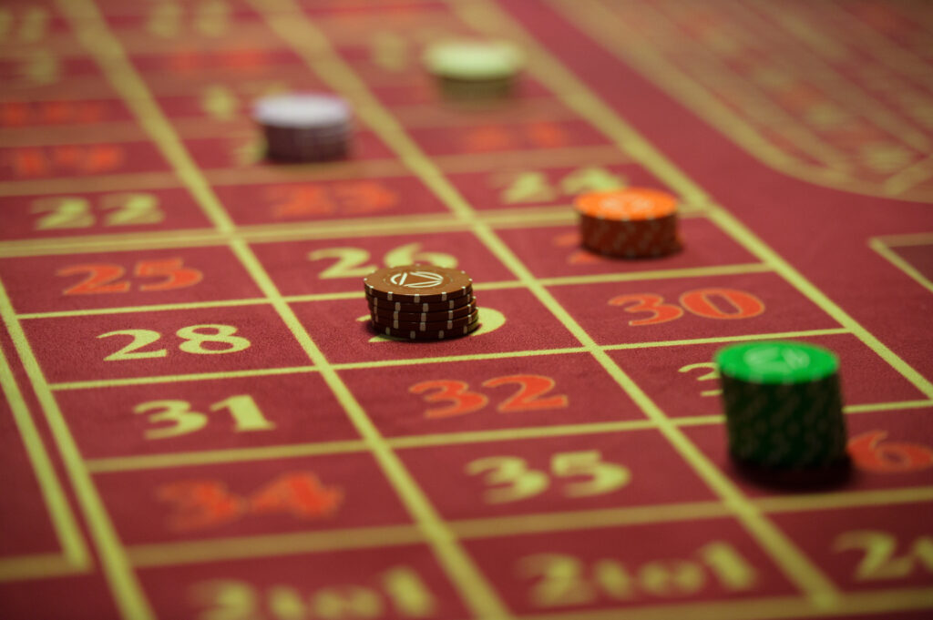 Close up of the betting area of a roulette table. Some numbers have casino chips on them.