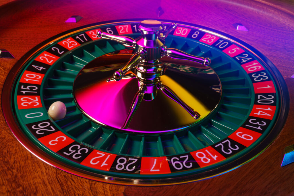 Close up of a roulette wheel with the ball on the zero pocket.