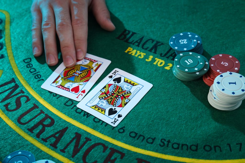 A photo of a blackjack table with two cards and casino chips placed on top.