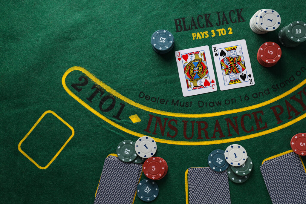 Close up of a blackjack table with playing cards and casino chips on it.