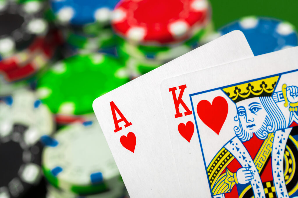 In the foreground are the Ace of Hearts and King of Hearts. In the background are blurred casino chips.