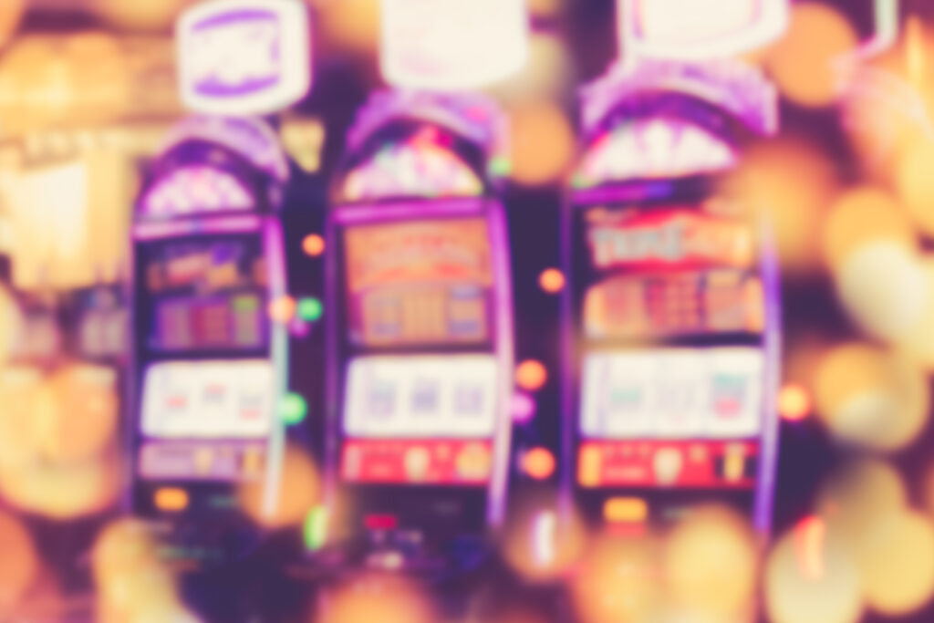 Three slot machines in a casino. The image is blurred.