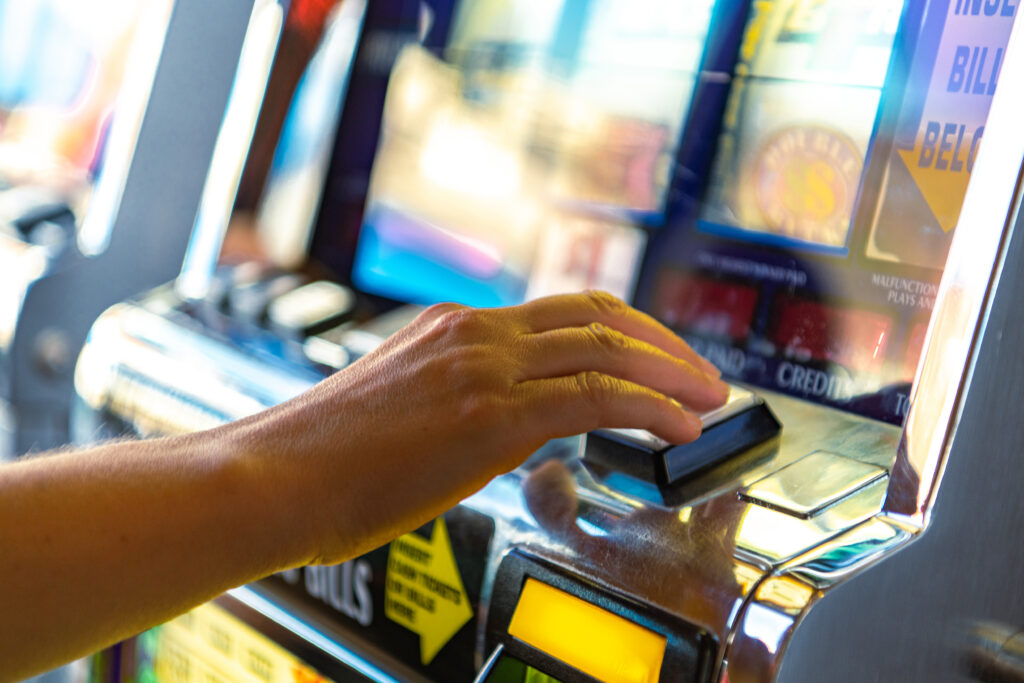 Person playing a slot machine; only their hand is in frame.