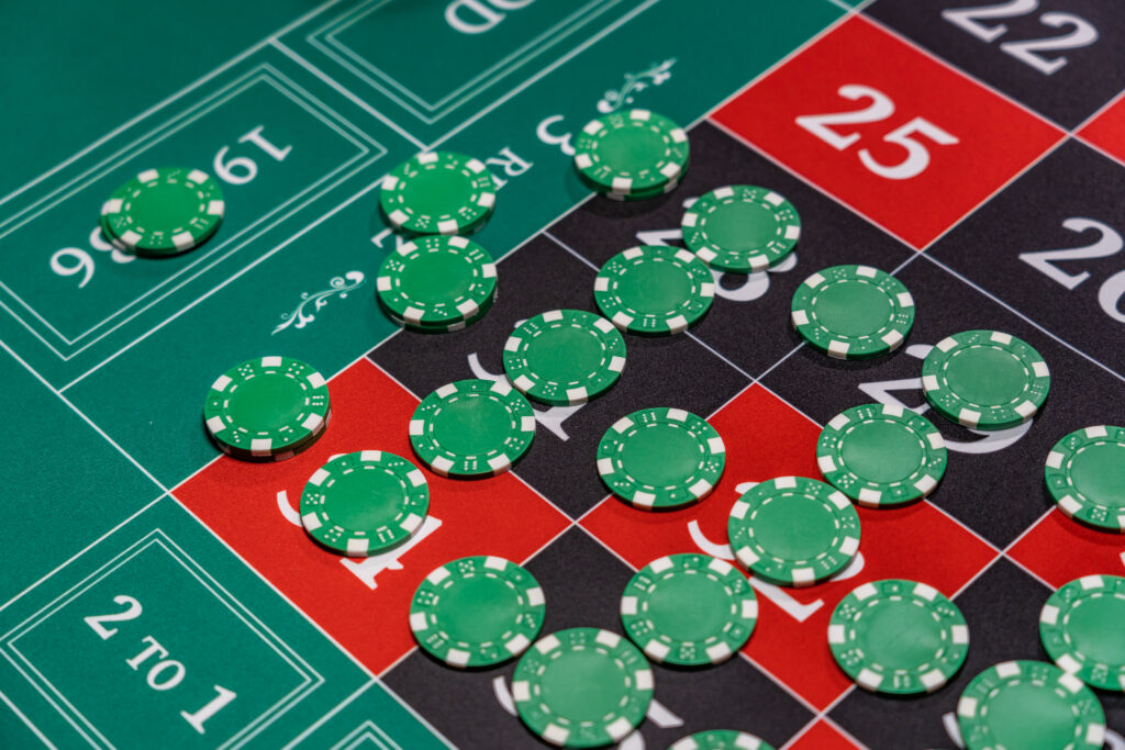 Green casino chips on the numbers of a racetrack of a roulette table.