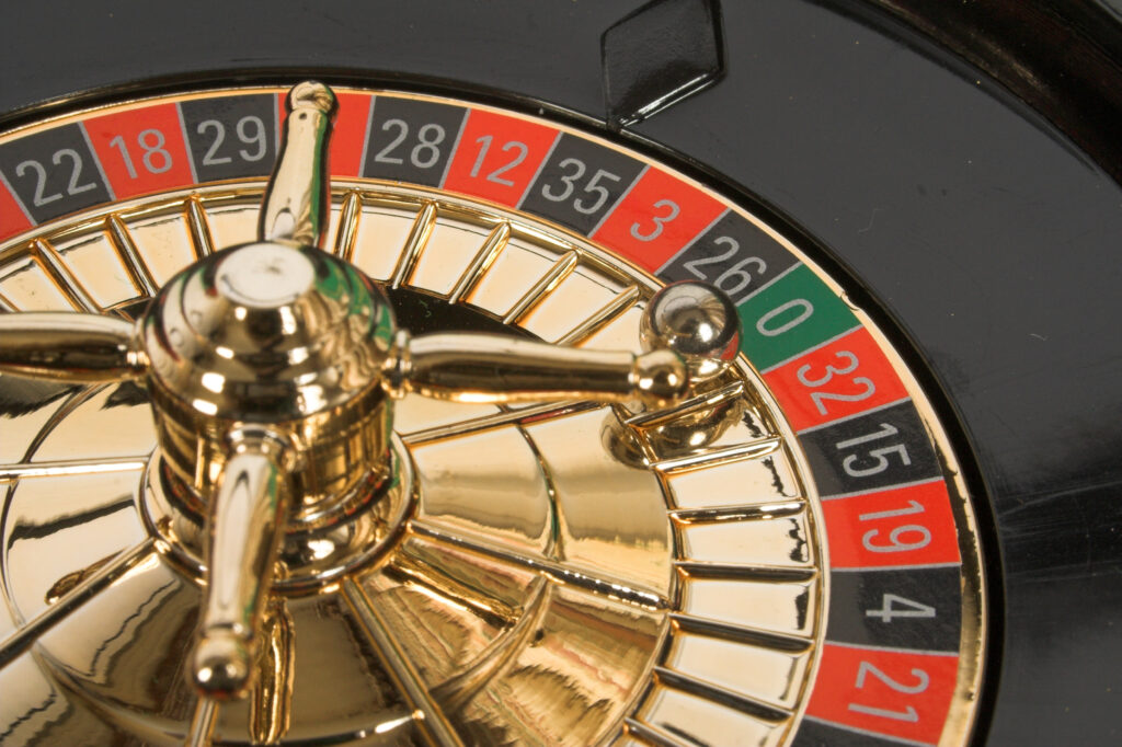 Close up of a roulette wheel with a static golden ball on zero.